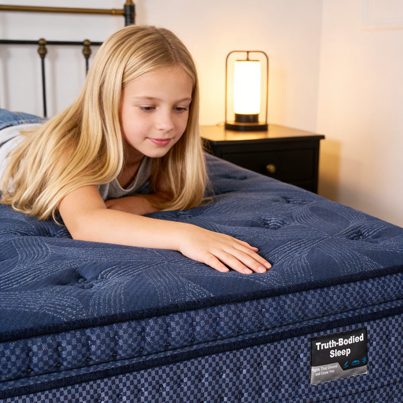 Young girl lying on a blue mattress with 'Truth-Bodied Sleep' branding in a bedroom setting.