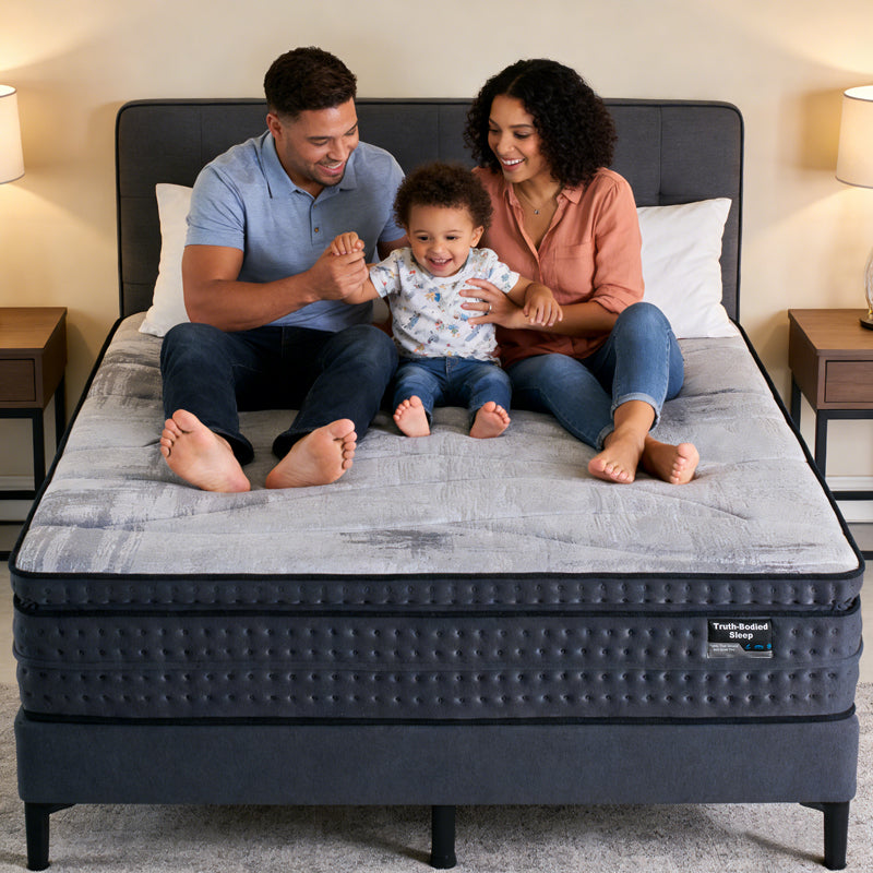 Family sitting on a mattress in a bedroom setting